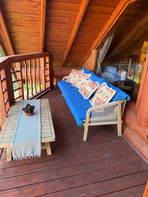 Balcón techado con sofá y mesa, junto al dormitorio