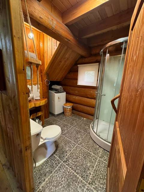 Baño con ducha, lavadora y piso de piedra